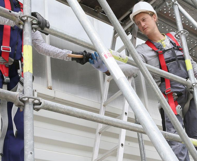 due operatori che costruiscono ponteggi portati da camion bilici